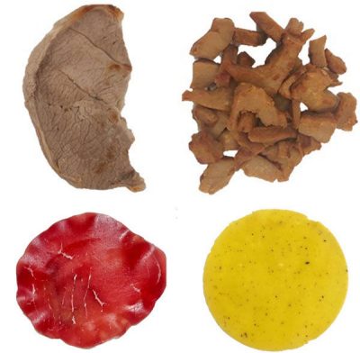 Clockwise from top left: a grayish-pink cooked slice of veal, several pieces of tan plant-based steak, a yellow slice of plant-based bresaola, and a red slice of bresaola. 