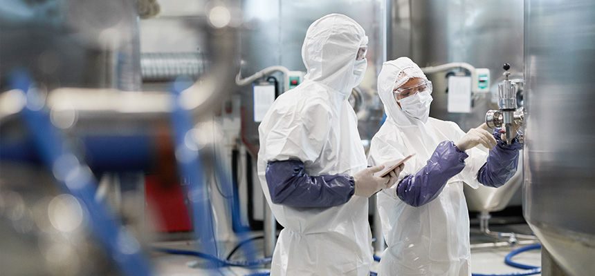 Two people wearing PPE working in a production facility 