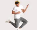 Teenager dancing and listening to music against light background