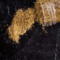 Gold glitter spilling onto dark area