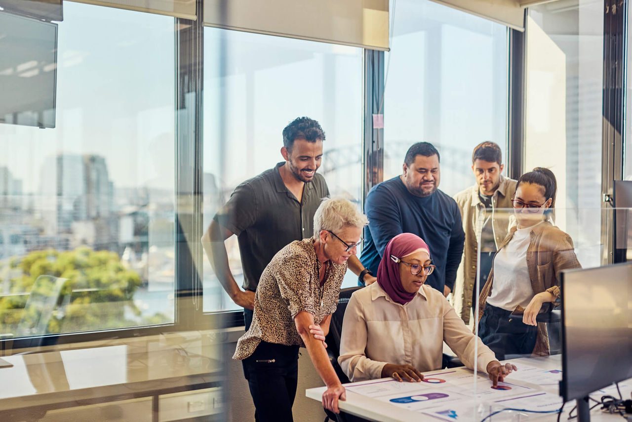 a photo of six people standing around a computer