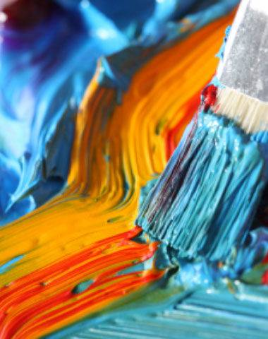 Paintbrush spreading multicolored paint