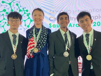 Four students with gold, gold, silver and gold medals from left to right.