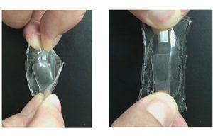 Two images of a clear film being twisted and stretched by a person’s fingers.