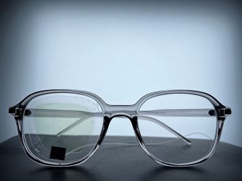 A pair of eyeglasses with a transparent, yellow sensor on one lens attached to a wire.