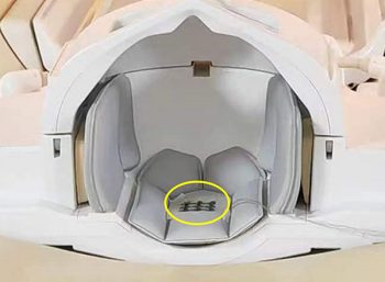 A sensor, attached to wires, and placed on a padded headrest within an MRI machine.